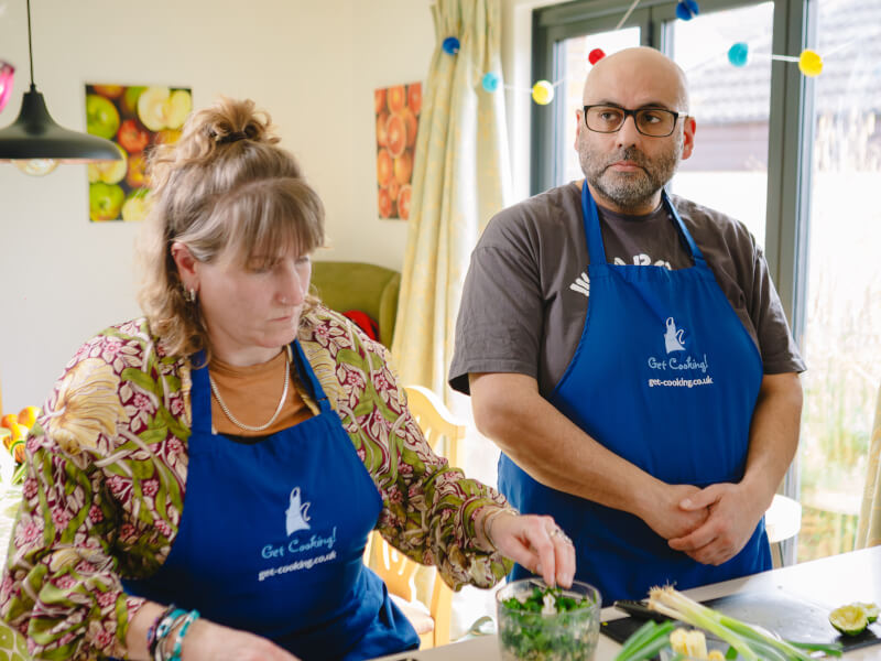 Two people listening to their teacher at a cooking class